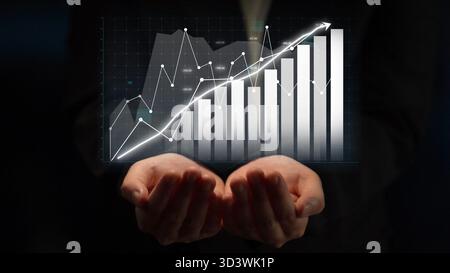 A pair of hands supports a digital graph displaying financial growth through bar charts and a trend line, symbolizing success and innovation in Stock Photo