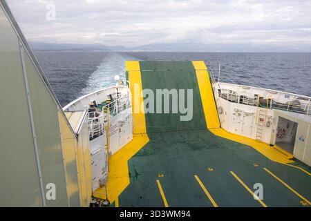 ROGAC, CROATIA, 10.22.2025:Cars line a ferry deck on a busy vehicle voyage. Green floor, bright yellow markings, and multiple parked cars create a cro Stock Photo