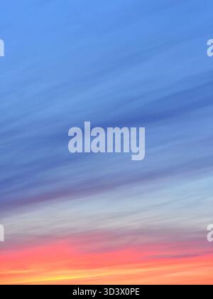 Cirrostratus at sunset. High clouds with shades ranging from orange to blue. A gradient of colors from deep orange at the horizon to light blue above. Stock Photo