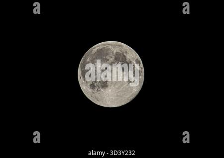 The moon's surface is visible with craters and textures, set against a dark background Stock Photo