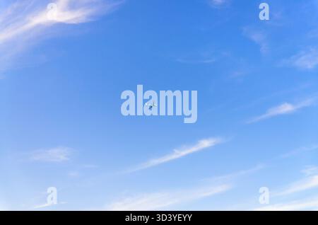 Airplane takes off into a blue sky with white clouds, Passenger plane aircraft flying across blue sky background, aircraft gaining altitude, view from Stock Photo
