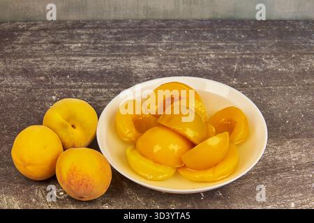 Half-cut peaches, canned preserve. Close-up photograph with copy space on a rustic background. Stock Photo