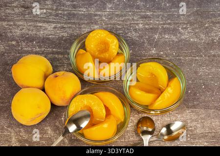 Half-cut peaches, canned preserve. Close-up photograph with copy space on a rustic background. Stock Photo