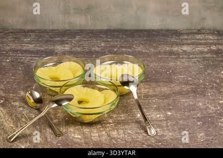 Sliced ​​pineapple, canned preserve. Close-up photograph with copy space on a table against a rustic background. Stock Photo