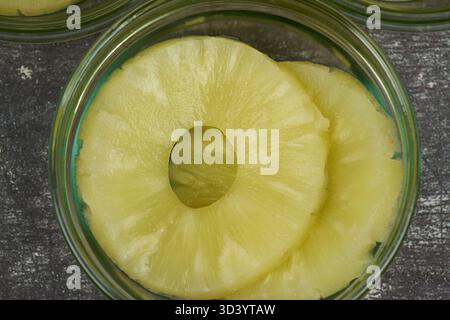 Sliced ​​pineapple, canned preserve. Close-up photograph with copy space on a table against a rustic background. Stock Photo