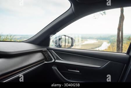 Car front side window. Looking at the river valley in the background through passenger door. Stock Photo