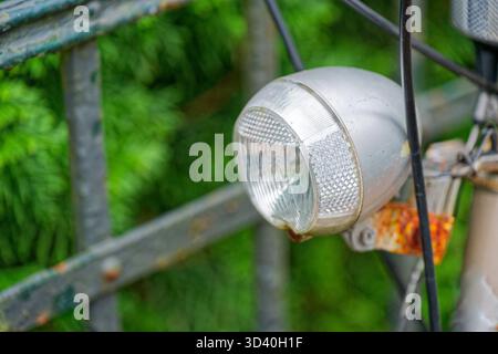A close view shows a front bike lamp fixed to the handlebar and aimed forward to light the road, the compact body and clear lens suggest simple daily Stock Photo