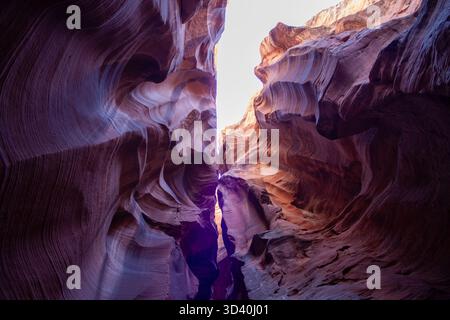 View looking up inside a slot canyon with curved sandstone walls and natural light illuminating the rock formations Stock Photo