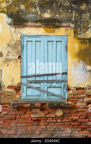 A blue boarded-up door on a vintage wall of an old building Stock Photo