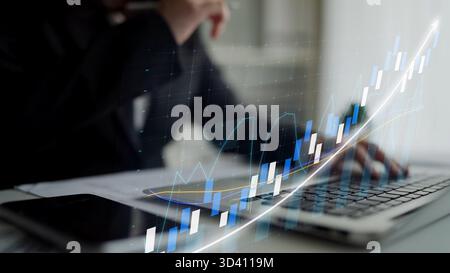 A business professional engages with financial data on a laptop, showcasing a digital growth chart. The image reflects analysis, strategy, and modern Stock Photo
