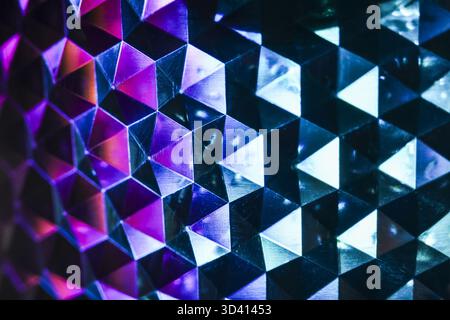 Mesmerizing abstract background with geometric pattern of vibrant purple and blue triangles. This futuristic design has cool neon light effect on dark Stock Photo
