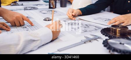 A dynamic scene showcasing a collaborative engineering meeting where hands interact over technical drawings and tools. Professionals engage in active Stock Photo