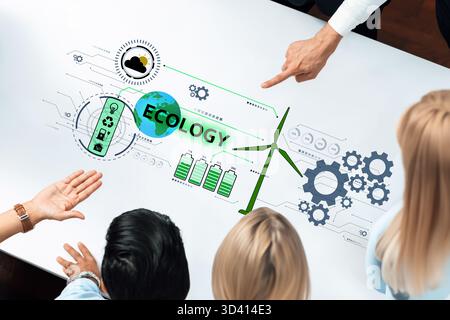 A diverse team collaborates over a table filled with graphics on ecology and renewable energy, showcasing innovative solutions for a sustainable Stock Photo