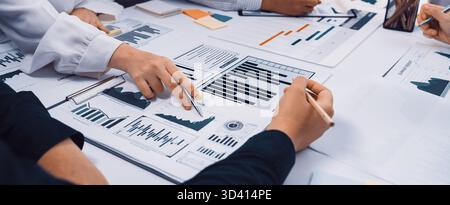 A group of diverse professionals engages in a collaborative session analyzing business reports and data trends. Various charts and graphs highlight Stock Photo