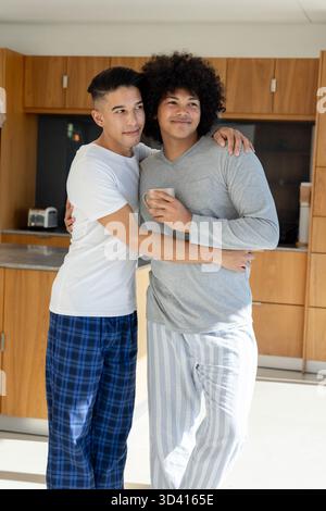 Embracing two men standing in modern kitchen, with coffee mug and countertop toaster Stock Photo