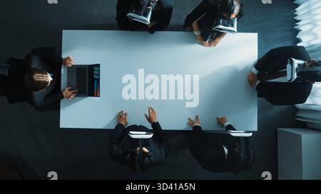 Top down aerial view of diverse data analysts wearing VR headset and stand around table while using hand gestures to manipulate the data streamed live Stock Photo