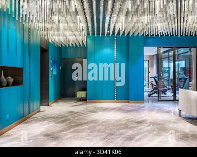 Vibrant interior with red-blue walls, glass chandelier, and marble floor. Stock Photo