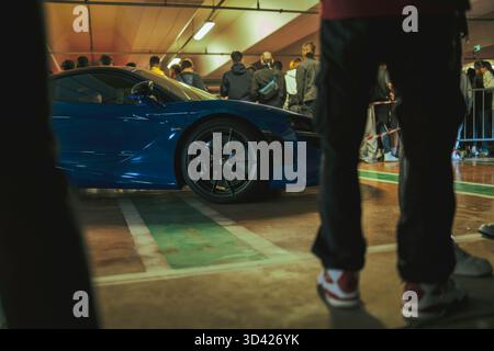 Milan, italy 28 october 2025: crowd admiring a sleek blue mclaren supercar indoors at an exclusive automotive event, showcasing luxury performance and Stock Photo