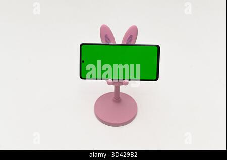Bunny-ear pink stand holding smartphone horizontally with green display. Symmetrical setup designed for video production or digital content mockups. s Stock Photo