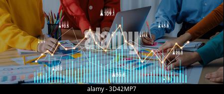 Diverse business team collaborates on data analysis using charts and graphs in a modern workspace filled with colorful stationery and creative ideas Stock Photo