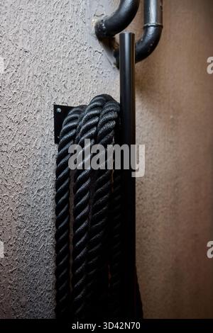 Industrial workspace with tactile elements, Black cord hanging on metallic hook setup, Workshop storage featuring gritty surface textures and subdued Stock Photo