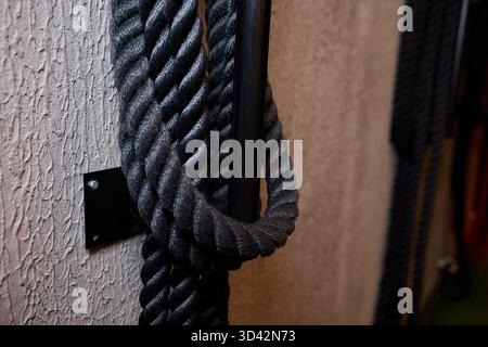 Industrial workspace with tactile elements, Black cord hanging on metallic hook setup, Workshop storage featuring gritty surface textures and subdued Stock Photo