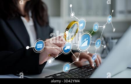 A business analyst examines data with a magnifying glass, surrounded by digital icons and charts, symbolizing technology and information in a modern Stock Photo