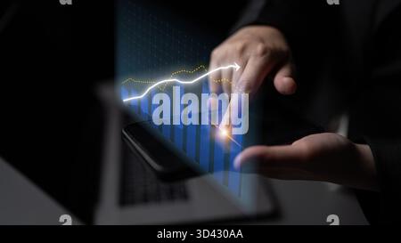 A business professional interacts with a smartphone displaying dynamic graph trends, illustrating financial growth in a modern office. The sleek Stock Photo