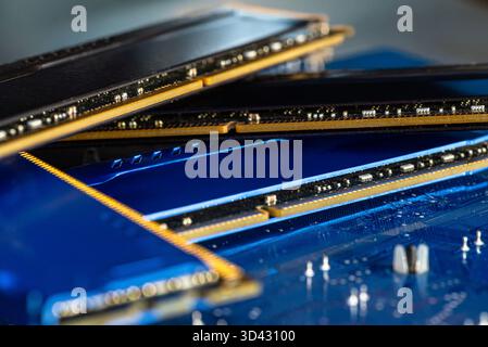 Four DDR memory chips in different colors lying on a blue printed circuit board. Stock Photo
