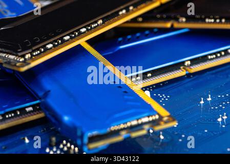 Four DDR memory chips in different colors lying on a blue printed circuit board. Stock Photo