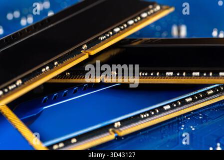 Four DDR memory chips in different colors lying on a blue printed circuit board. Stock Photo