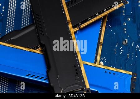 Four DDR memory chips in different colors lying on a blue printed circuit board. Stock Photo