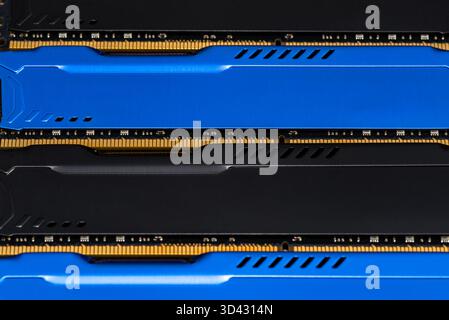Four DDR memory chips in different colors lying on a blue printed circuit board. Stock Photo