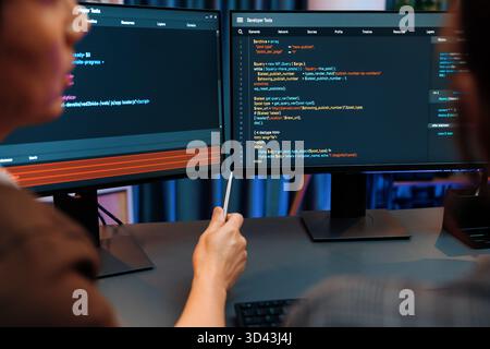 Smart IT developer looking at coding program application on computer screen of online website at back side, analyzing intelligent database system Stock Photo