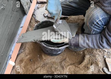 A builder faces the basement of a house with a wild stone. Flat for cladding, tabata on the construction site. Stock Photo