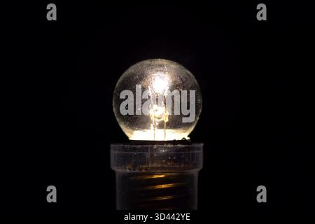 small three volt incandescent light bulb. Burning lamp. Stock Photo
