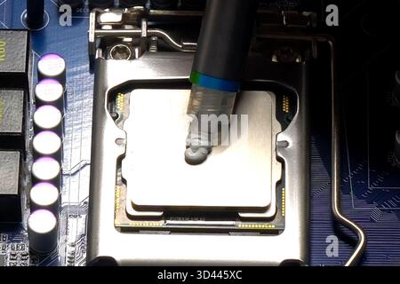 Drawing thermal paste on the computer processor. Installing a cooling system on a CPU processor Stock Photo