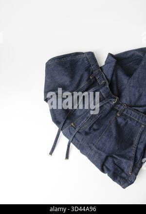 Denim jeans randomly stacked on white background, copy space Stock Photo