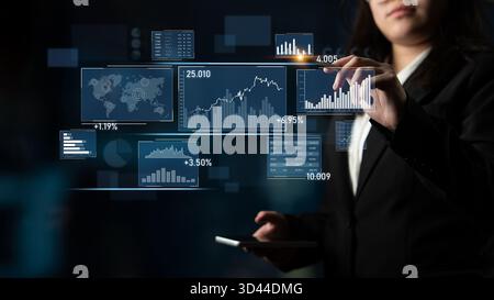 A businesswoman interacts with a digital touchscreen displaying various charts, graphs, and world data in a modern office setting, illustrating Stock Photo