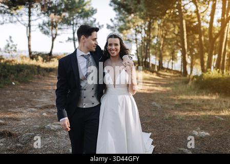 Portrait of a husband placing his arm over his wife's shoulder while walking through the woods Stock Photo