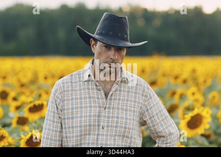 Man farmer standing in a sunflower field Stock Photo