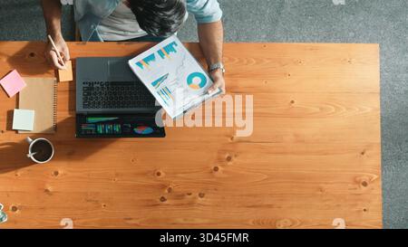 Skilled businessman writing idea on colorful sticky notes while looking at data analysis. Caucasian project manager working on laptop while taking a Stock Photo