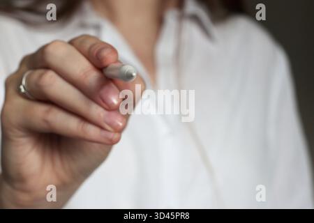 Close up of female hand holding a stylus, ready to draw or write on a screen. Concept of creativity, digital design, concentration, and focus in profe Stock Photo