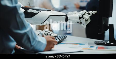 A close-up view of a robotic arm interacting with a computer, illustrating the seamless integration of advanced technology in modern work environments Stock Photo