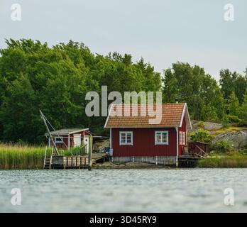 Lakeside Swedish cabin in lush green forest Stock Photo