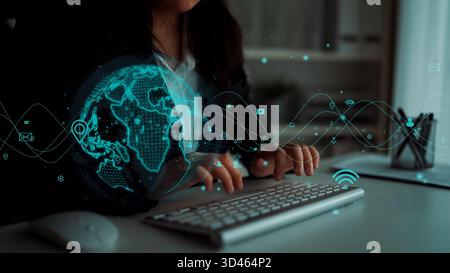 A business professional engages with a keyboard in a contemporary workspace, featuring a digital holographic globe and connectivity graphics to Stock Photo