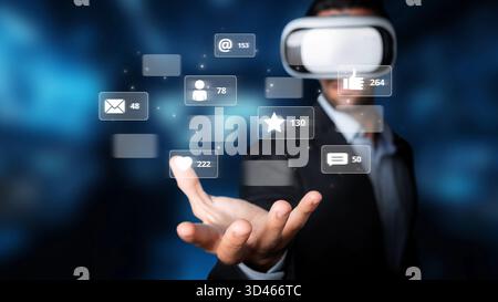 Businessman wearing virtual reality glasses interacts with floating social media icons, symbolizing innovation in communication and technology in Stock Photo