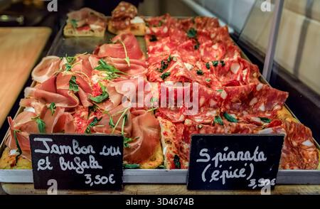 Slices of fresh pizza with ham and buffalo mozzarella or spianata spicy Italian salami at a fast food restaurant in Old Town of Nice, South of France Stock Photo