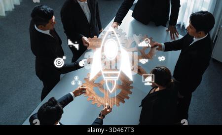 A diverse team of professionals collaborates on innovative business strategies, using gears and a rocket symbol to symbolize growth and success in a Stock Photo