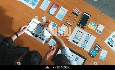 Software developer team holding software icon and discussing about Ux Ui design for mobile phone interface. Top view of programmer work together to Stock Photo